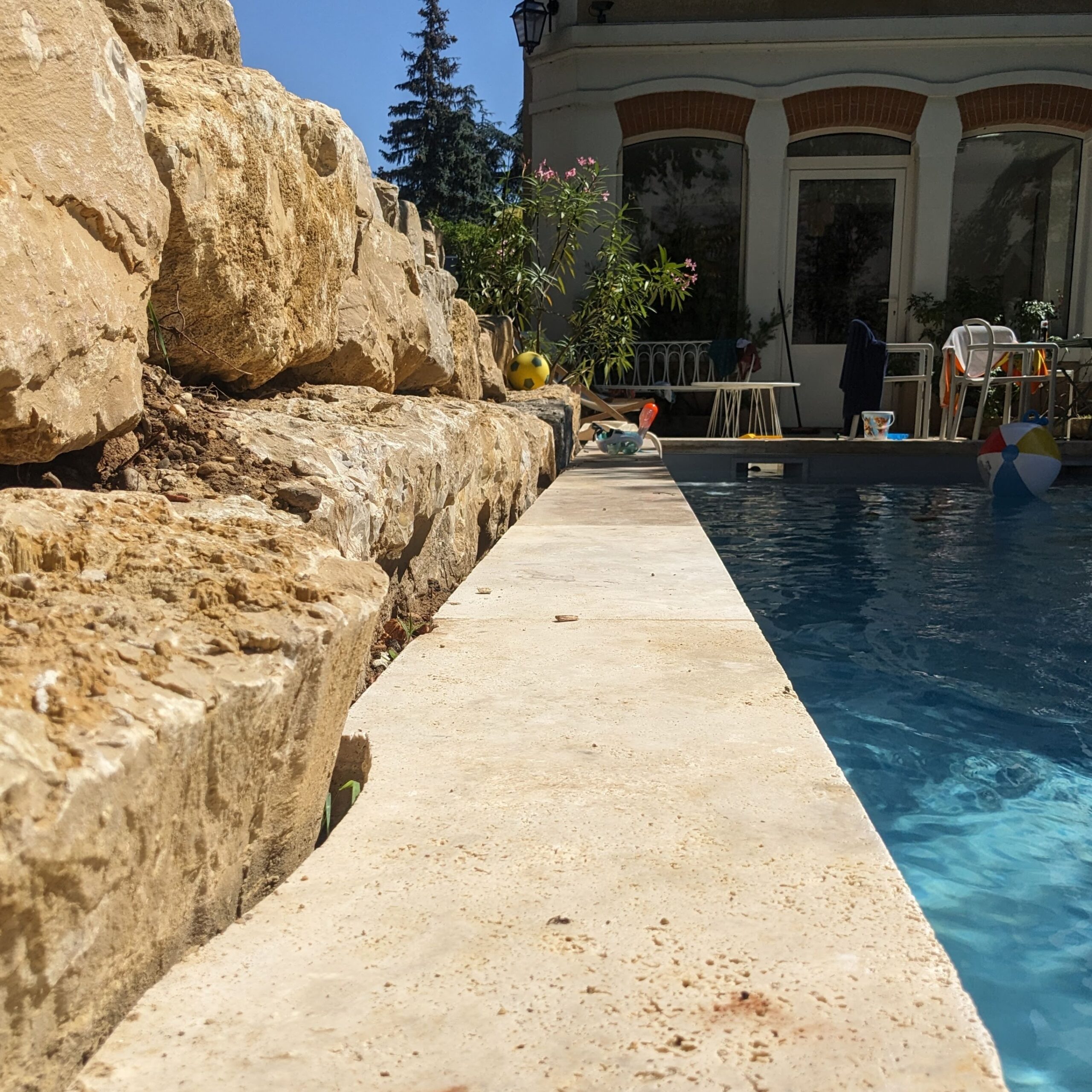 Enrochement en bord de piscine margelle travertin