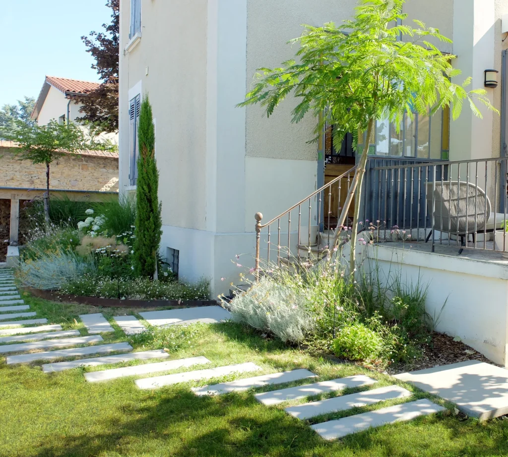 Façade de la maison et jardin Concretia à Saint-Didier-au-Mont-d’Or, avec dalles et massifs.