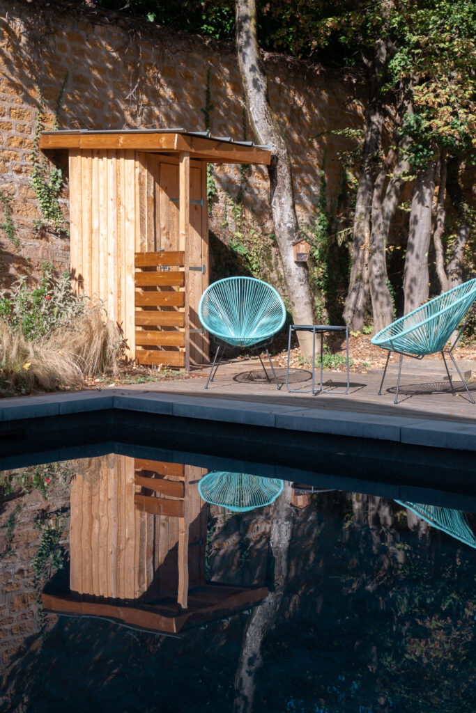 Petite construction en bois et fauteuils au bord de la piscine