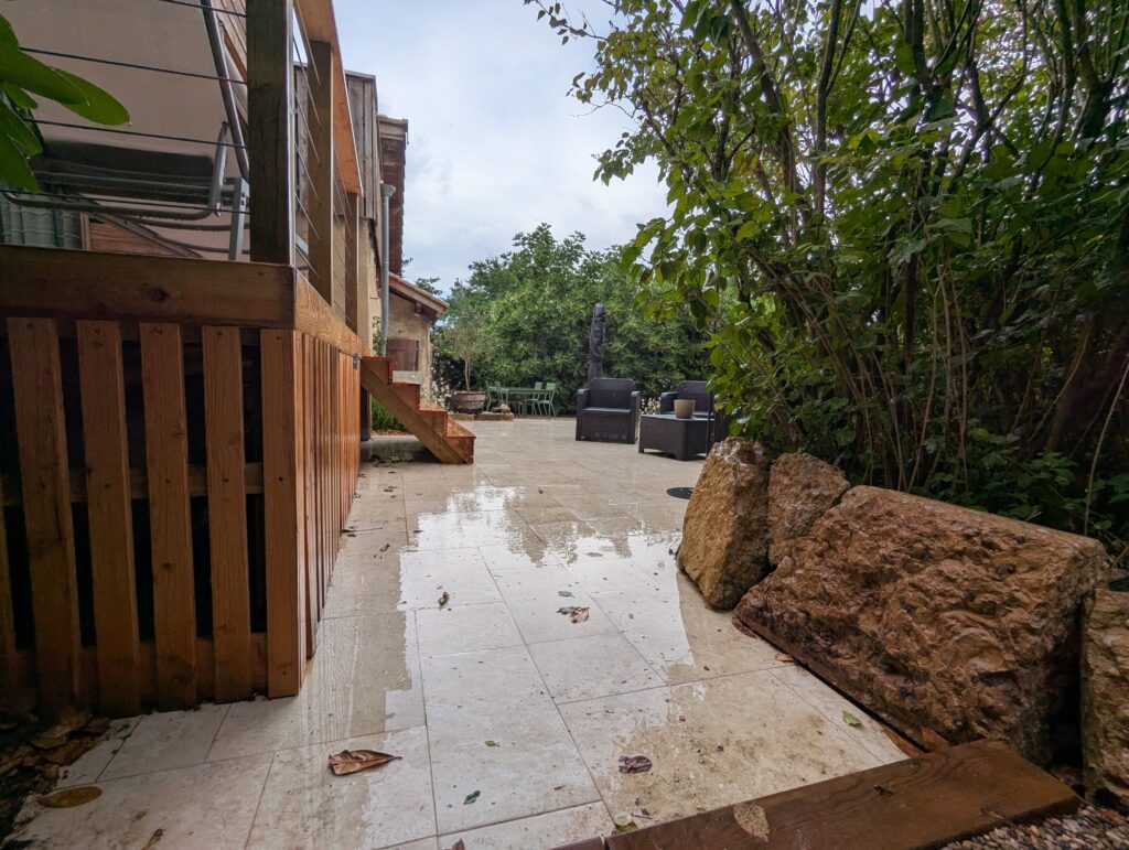 Entrée du jardin entre terrasse en bois, travertin et soutènement en pierres à Dardilly
