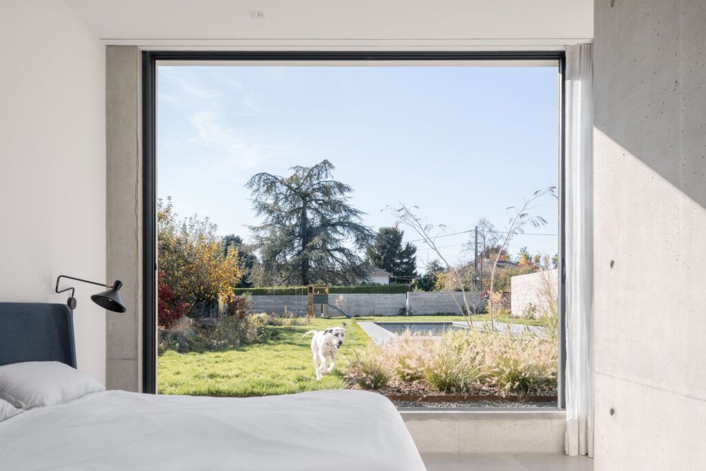 Vue du jardin et de la piscine depuis une chambre ouverte sur le paysage
