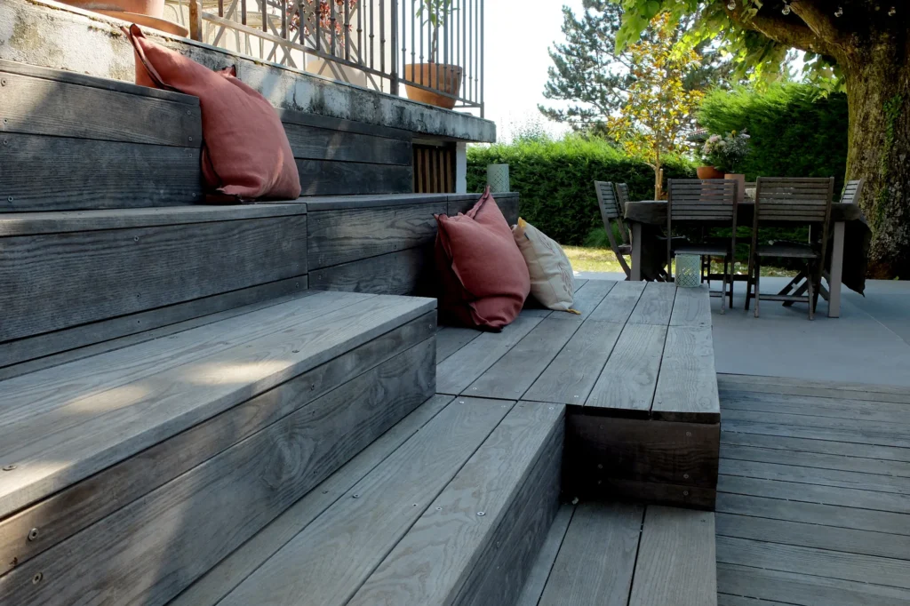 Gradins en bois avec coussins reliant les terrasses du jardin Concretia.