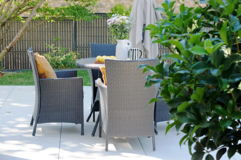 Table et fauteuils sur la terrasse de repas, encadrés de végétation dans le jardin Londres.